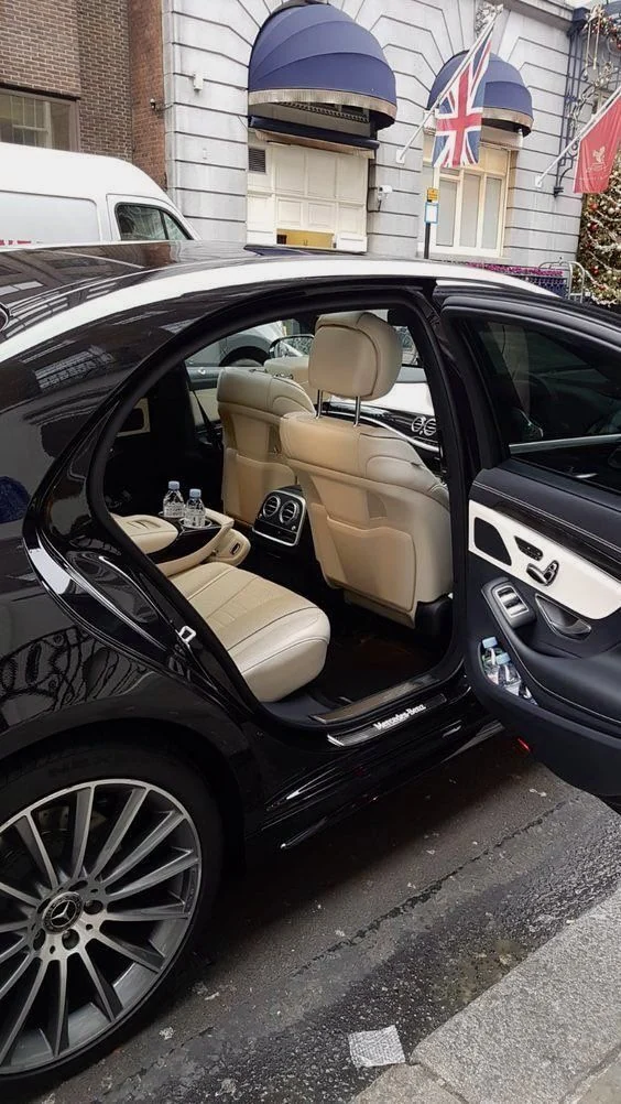 An open Mercedes-Benz door revealing a cream leather passenger interior outside a London hotel